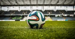 A leather football nestled in the center circle of a sun-drenched, empty football field